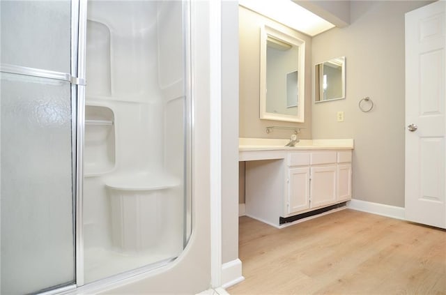 bathroom featuring a stall shower, vanity, baseboards, and wood finished floors