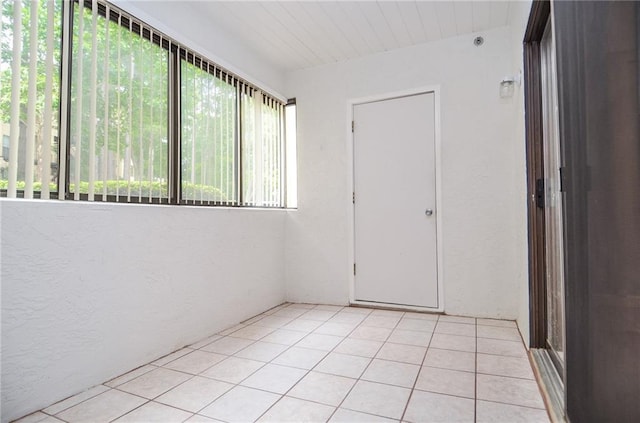 empty room featuring light tile patterned floors and a textured wall