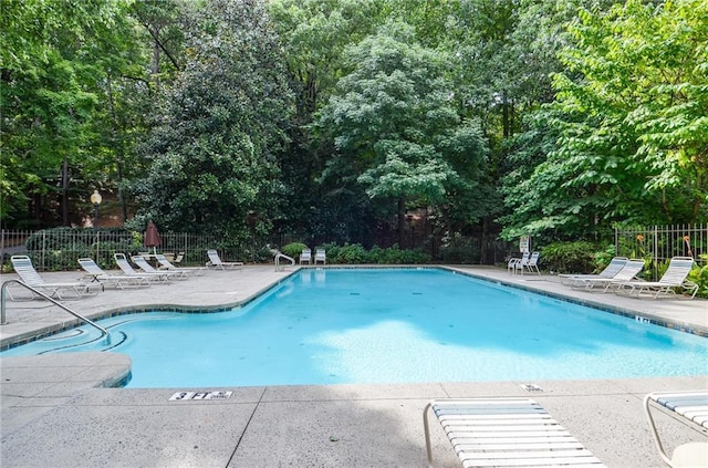 pool with a patio area and fence