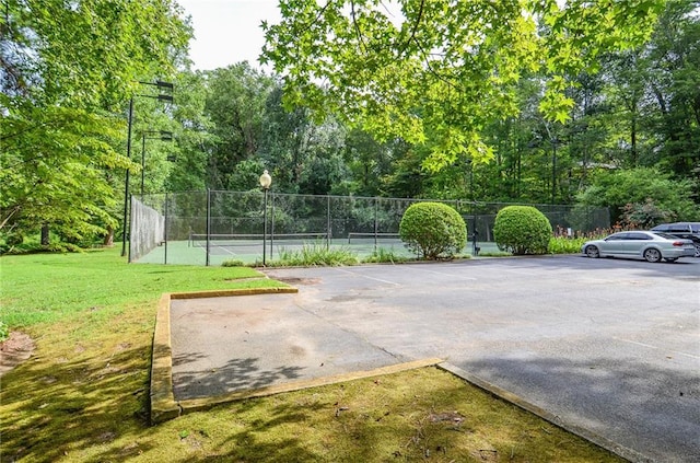 exterior space with a tennis court and fence