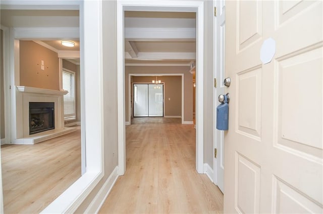 hallway featuring light wood-type flooring, crown molding, beamed ceiling, and baseboards