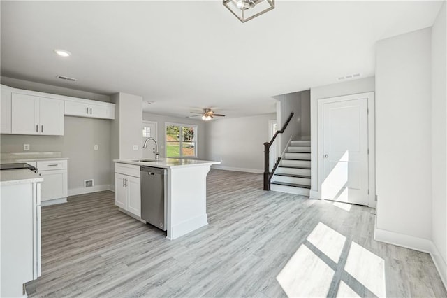 6075 Quail Mountain Trl, Gainesville, GA 30506 - kitchen with stainless steel dishwasher, light countertops, a sink, white cabinetry, and light wood-style floors