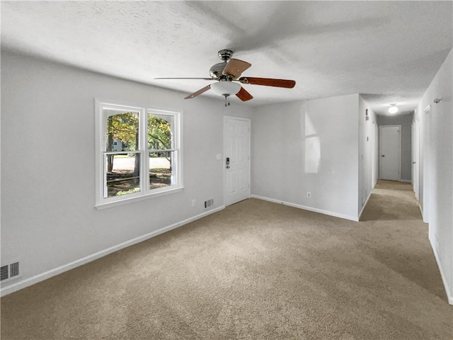 carpeted spare room featuring ceiling fan and a textured ceiling