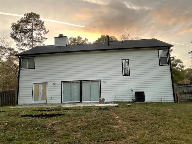 back house at dusk featuring central AC and a yard