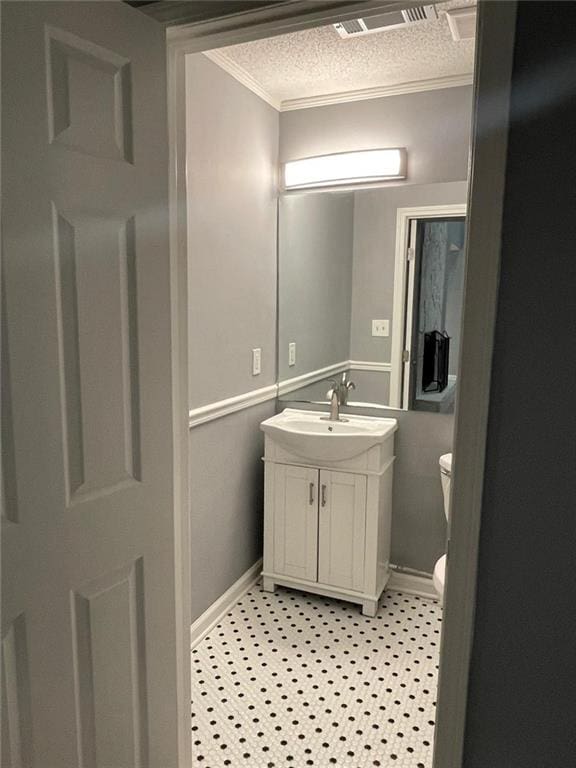 bathroom featuring a textured ceiling, vanity, toilet, and ornamental molding