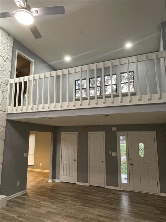 foyer with ceiling fan, wood-type flooring, and a towering ceiling