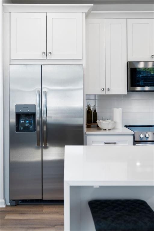 kitchen featuring appliances with stainless steel finishes, white cabinetry, and hardwood / wood-style floors