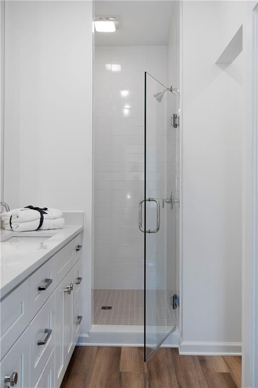 bathroom with hardwood / wood-style floors, vanity, and a shower with shower door