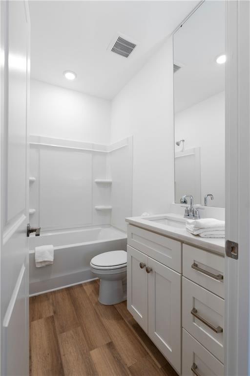 full bathroom with hardwood / wood-style flooring, vanity,  shower combination, and toilet