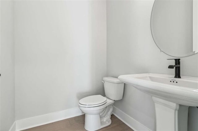 half bath with toilet, baseboards, and a sink