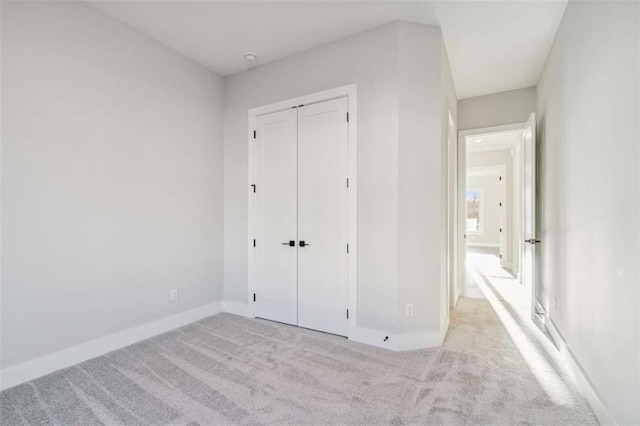 unfurnished bedroom with carpet, a closet, and baseboards