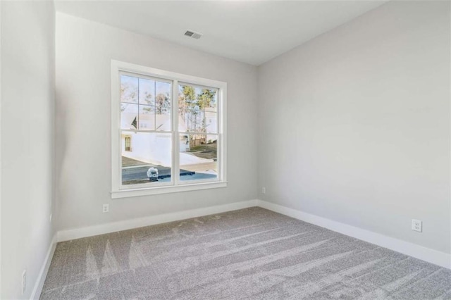 empty room featuring carpet, visible vents, and baseboards