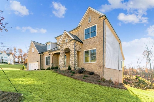 traditional home featuring an attached garage, a front lawn, brick siding, and stone siding