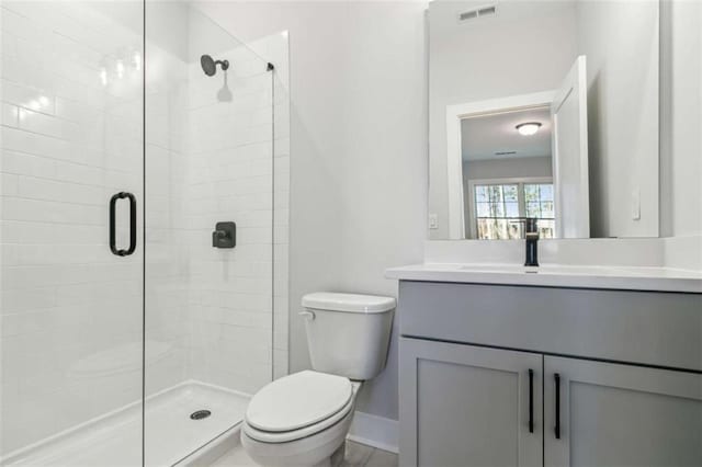 bathroom with toilet, a stall shower, vanity, baseboards, and visible vents
