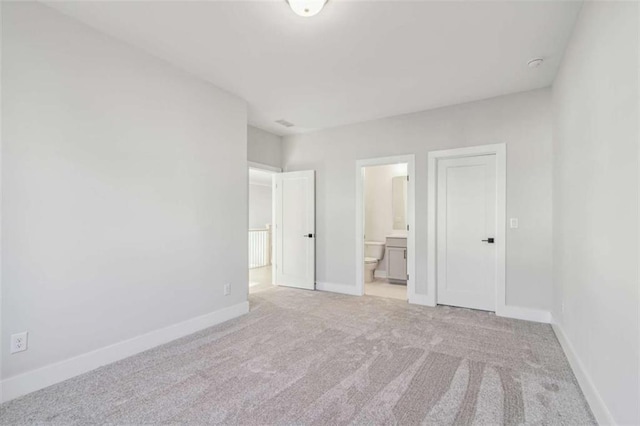 unfurnished bedroom with carpet flooring, baseboards, and connected bathroom