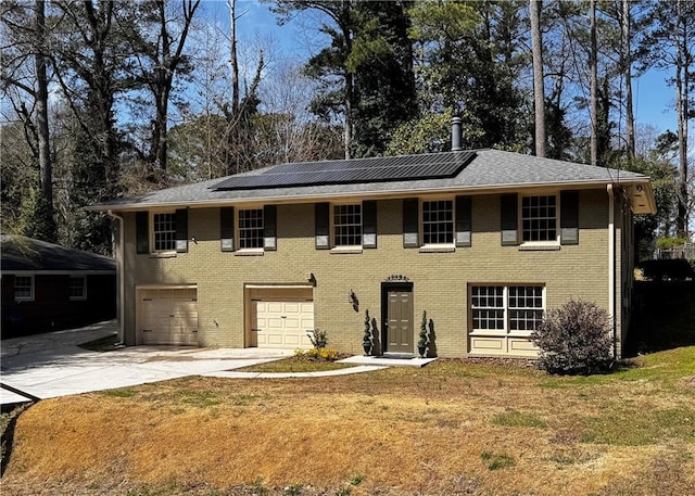 view of front of home with brick siding, driveway, and solar panels