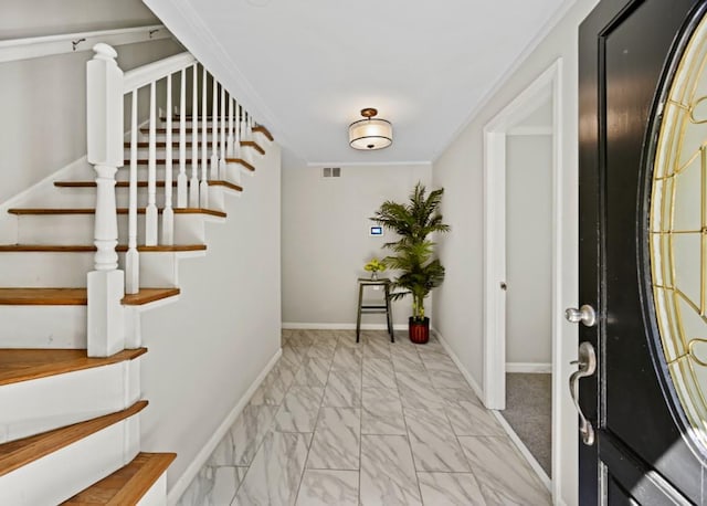 foyer with marble finish floor, ornamental molding, visible vents, and baseboards