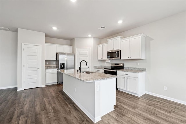 kitchen featuring dark wood-style flooring, a center island with sink, stainless steel appliances, visible vents, and a sink