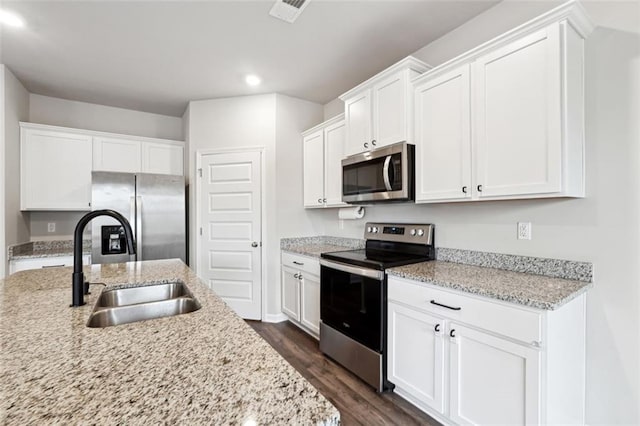 kitchen with visible vents, white cabinets, dark wood-type flooring, stainless steel appliances, and a sink