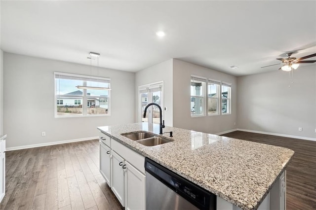 kitchen with a center island with sink, baseboards, dishwasher, dark wood-style flooring, and a sink