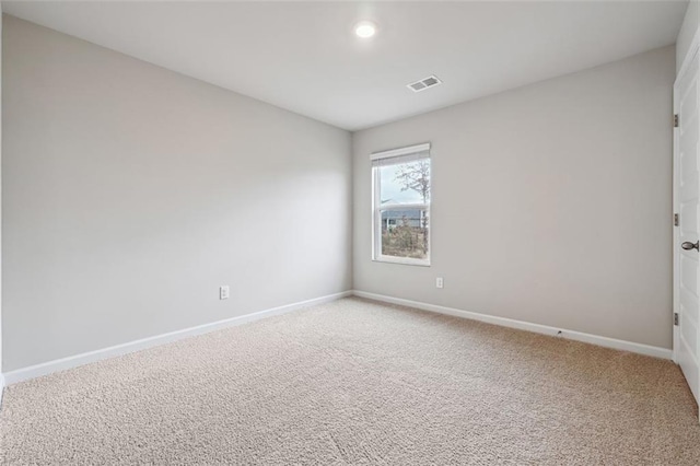 carpeted spare room with visible vents and baseboards