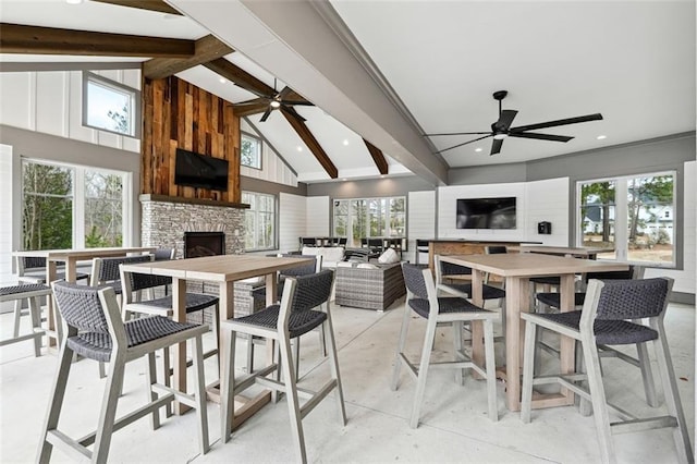 dining space with a wealth of natural light, high vaulted ceiling, beamed ceiling, and an outdoor stone fireplace