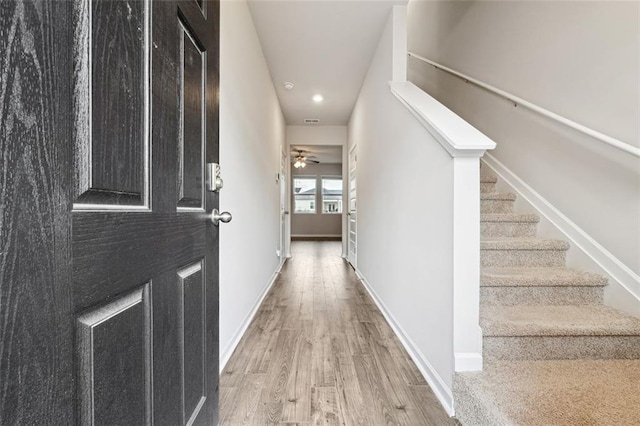 corridor with stairs, wood finished floors, and baseboards