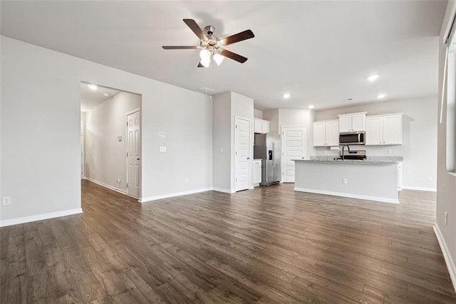 unfurnished living room with baseboards, dark wood finished floors, a ceiling fan, and recessed lighting