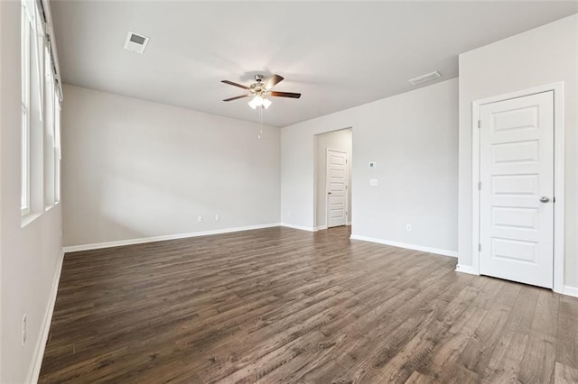 empty room featuring dark wood-style floors, visible vents, baseboards, and a ceiling fan