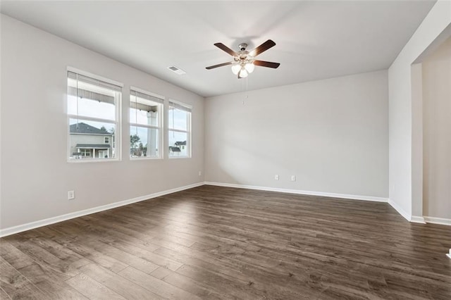 unfurnished room featuring dark wood-type flooring, a ceiling fan, visible vents, and baseboards