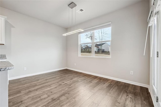 unfurnished dining area featuring wood finished floors, visible vents, and baseboards