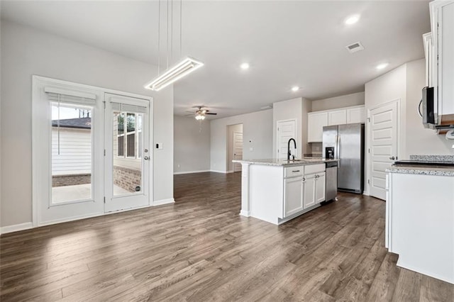 kitchen featuring stainless steel appliances, open floor plan, a kitchen island with sink, and dark wood finished floors