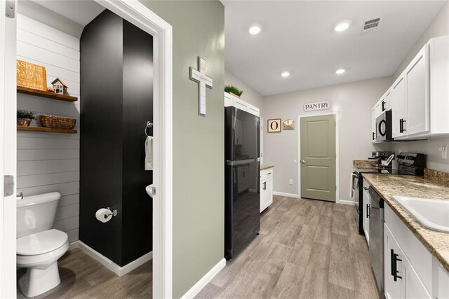 kitchen featuring sink, white cabinetry, black appliances, and light stone counters