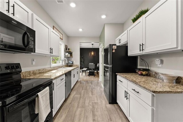 kitchen featuring black appliances, white cabinets, light hardwood / wood-style flooring, decorative light fixtures, and sink