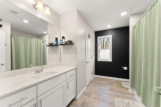 bathroom with baseboards, visible vents, wood finished floors, and vanity