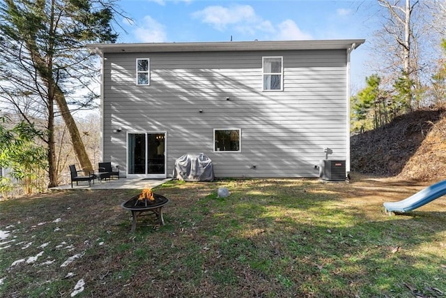 rear view of property with a playground, a lawn, an outdoor fire pit, a patio area, and central AC