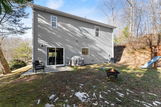 rear view of house with a fire pit, a patio, central AC, and a playground