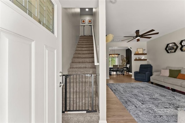 interior space with ceiling fan with notable chandelier, stairway, and wood finished floors