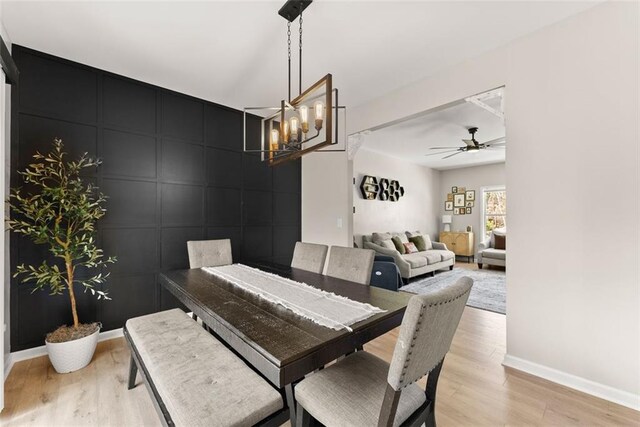 dining space with sink, light wood-type flooring, and a chandelier