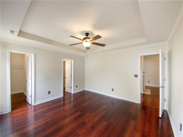 unfurnished room featuring a tray ceiling, ceiling fan, dark hardwood / wood-style flooring, and crown molding