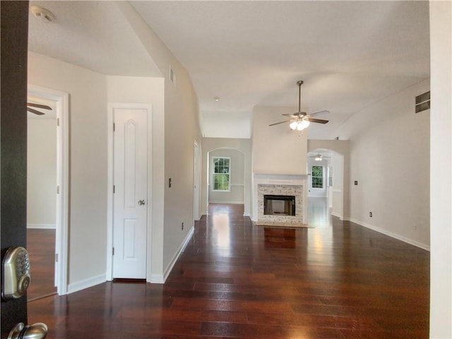 unfurnished living room with dark hardwood / wood-style floors, a stone fireplace, plenty of natural light, and lofted ceiling