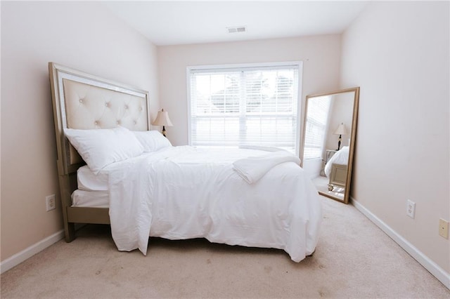 bedroom with baseboards, visible vents, and light colored carpet