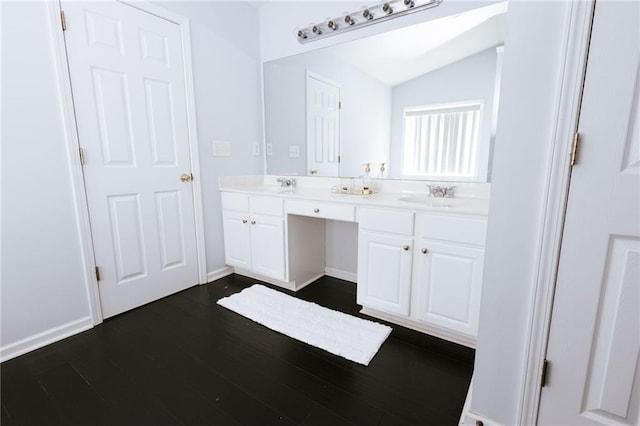 full bath with vaulted ceiling, double vanity, a sink, and wood finished floors