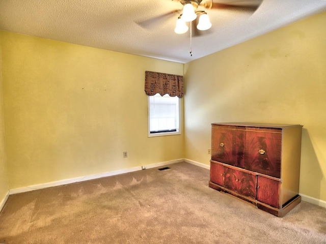 carpeted empty room featuring ceiling fan and a textured ceiling