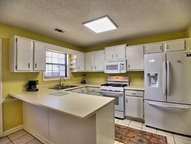 kitchen featuring sink, light tile patterned floors, kitchen peninsula, white appliances, and white cabinets