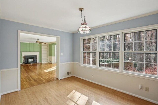 unfurnished dining area with ceiling fan, ornamental molding, and hardwood / wood-style flooring