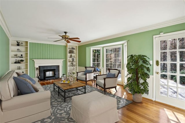 living room with hardwood / wood-style flooring, ceiling fan, crown molding, and built in shelves