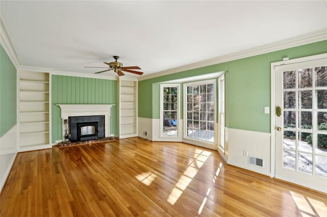 unfurnished living room featuring light hardwood / wood-style floors, plenty of natural light, and crown molding