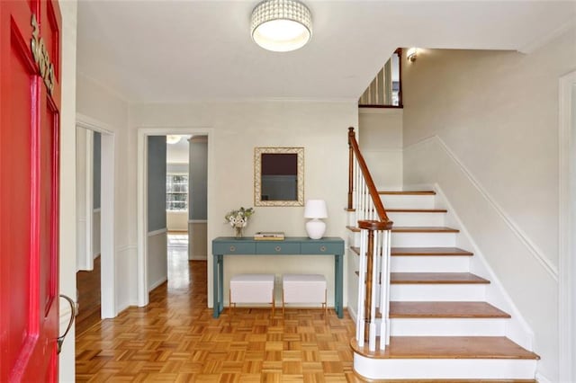 stairs featuring parquet floors and crown molding