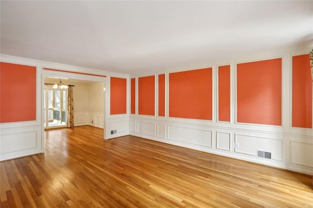 spare room featuring wood-type flooring, an inviting chandelier, and ornamental molding